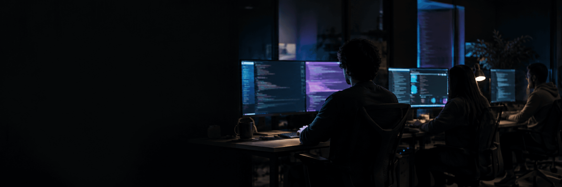 The AigentFlow.io development team working in a dark studio at night, screens glowing cyan and violet